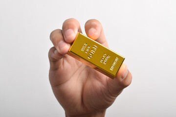 Hand holding Gold bar isolated on white background, with clipping path