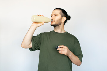 Portrait of young happy man drinking water from steel thermo bottle on white background.