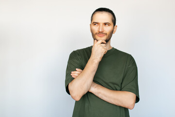 Portrait of young thoughtful man, touching his chin while looking away, on white background.