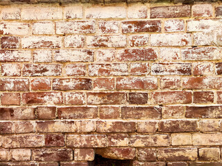 Close-up view of a weathered brick wall showcasing a mix of red and white bricks under bright...
