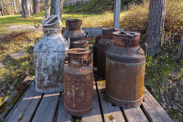 A collection of weathered milk cans rests on a rustic wooden platform,