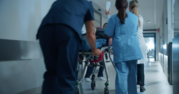 Nurse Running Towards the Team of Medics in Modern Hospital. Scene with Emergency Staff Working as a Unit to Transport a Stretcher Through the Hallway to the Operating Room