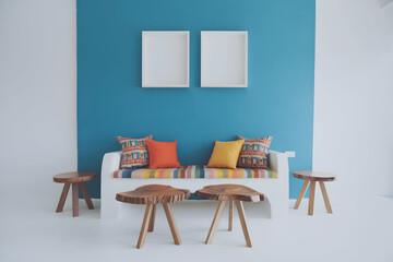 Minimalist living room with a vibrant blue wall, white bench, and elegant frames.
