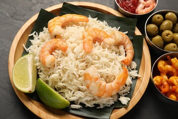 Pieces of banana leaf with rice, shrimps and lime on grey textured table, closeup