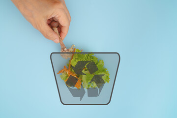 Hand put leftover food   in bin with recycle symbol on blue background, Food loss , waste, recycle,...