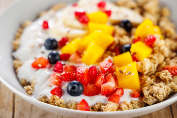 close up on bowl with granola, yogurt and fresh fruits. healthy eating