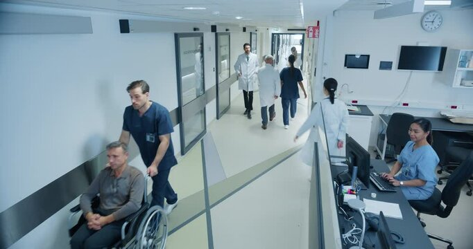 High Angle CCTV Footage with a Busy Hallway with Reception Desk of a Hospital Building, Diverse Female and Male Staff Members Walking, Working. Professional Nurses, Doctors and Personnel at Work