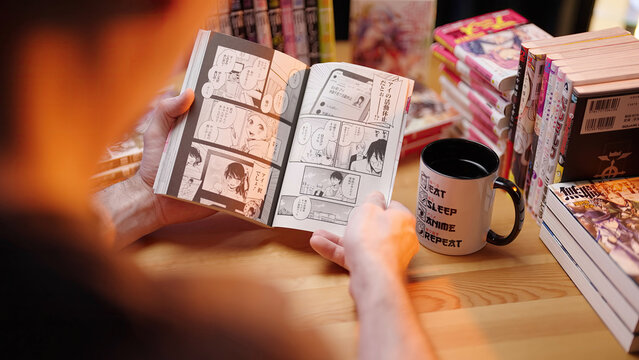 Person reading popular Japanese manga comic Oshi no Ko, over shoulder view