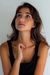 Beautiful woman model wearing a tight black shirt, looking up at an angle, thinking pose.