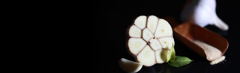 Fresh garlic clove on black background. Garlic is rich in vitamins, useful spring, good spices. Garlic sliced on a dark background. Raw sliced garlic.