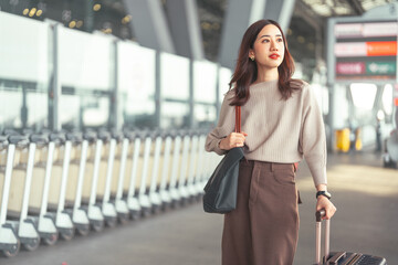 Standing tourist woman with travel luggage waiting at bus terminal for transport on day