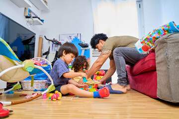 Fototapeta premium father playing with his two sons in the living room