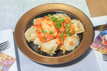 National Uyghur manti with tomato sauce and greens close-up
