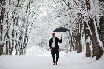 A man on a walk in the park. Young man with in the winter snowfall.