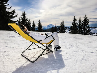 Girl sitting on the lounge chair on snow