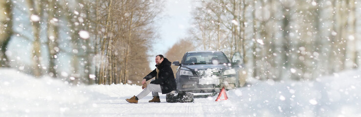 A man near a broken car on a winter day