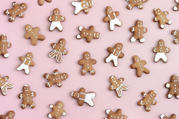 Christmas pattern of gingerbread men cookies  on pastel pink background. Flat lay, top view of easy homemade real cookies. 