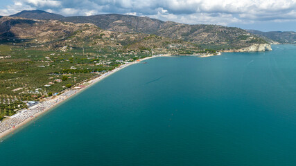Fototapeta premium Aerial view of the beach of Mattinata, in the province of Foggia, Puglia, Italy. The beach is crowded with many umbrellas and beach clubs on this beautiful sunny summer day. Holidays on Gargano.