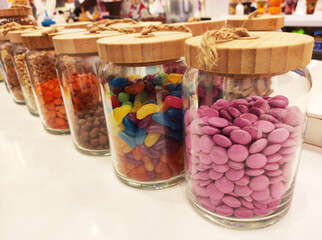 Various ice cream additives, topping in the form of small candies and muesli, in transparent jars on the shop window