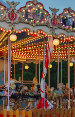 Brightly lit carousel canopy with intricate designs, glowing bulbs, and red and white striped pole