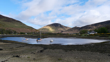 Scenic view of Isle of Arran with boats on loch and mountainous landscape of Inner Hebrides in Western Scotland UK
