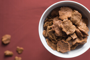 Overhead view of kuli-kuli in a white bowl, top view of nigerian groundnut cakes in a bowl, fresh homemade nigerian kulikuli in a ceramic bowl
