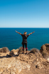 Girl standing on the edge of a cliff with outstretched arms