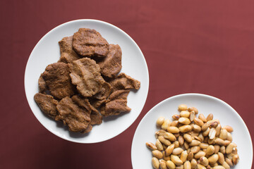 Obraz premium Overhead view of kuli-kuli and groundnut on a white plate, top view of nigerian groundnut cakes on a plate, fresh homemade nigerian kulikuli on a ceramic plate
