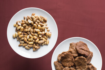 Overhead view of kuli-kuli and groundnut on a white plate, top view of nigerian groundnut cakes on a plate, fresh homemade nigerian kulikuli on a ceramic plate