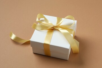 Beautiful gift box tied with bow on color background 