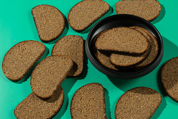 Rye bread slices and bowl on teal background