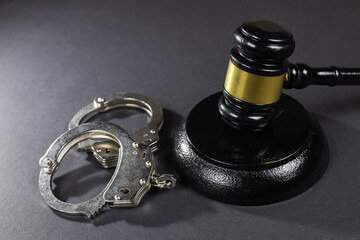 Judge's gavel and handcuffs on a dark background. Judge's gavel and handcuffs
