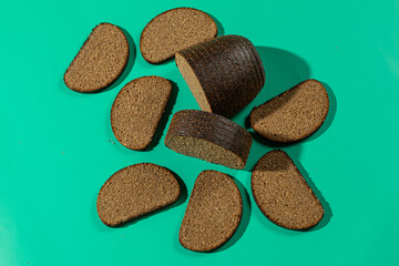 Sliced dark rye bread on teal background