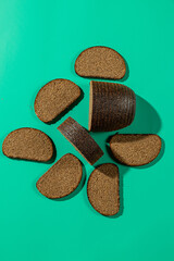 Sliced dark rye bread on teal background