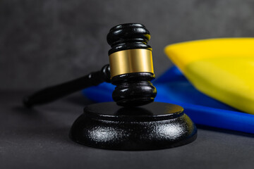 Judge gavel and flag of Ukraine on dark background. Blue yellow Ukrainian flag and wooden judge...