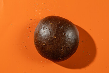 Round artisan rye bread on vibrant orange background