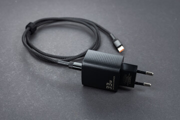 Black phone AC charger and USB cable on dark background