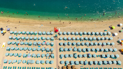 Aerial view of a beach club with blue umbrellas in Puglia, Italy. The beach is sandy and crowded on...