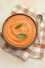 Delicious sweet potato soup with spices and basil on beige textured table, top view