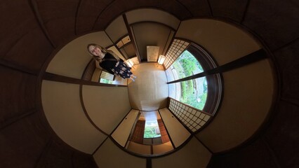 Woman standing in a traditional Japanese room with sliding doors and a serene view of nature during daytime