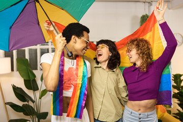 Multiethnic friends celebrating with rainbow umbrella and flag