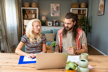 Confident couple office workers work at home, young caucasian couple sit at table using laptop...