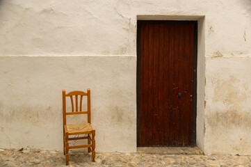 Rustic wooden chair beside an aged wooden door in an alley