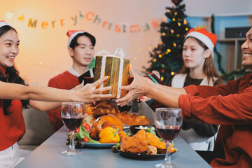 Group of young Asian man and women as friends having fun at a New Year's celebration, holding gift...