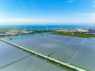 An aerial view shows a solar power plant floating on calm water, with rows of solar panels spread...