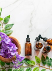 A mortar with some purple flowers and some amber vials of essential oils on a white marble surface. Some leaves surrounding them