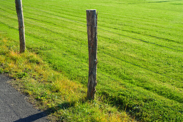 Piquetes de madera y valla de alambre en pradera de hierba cortada