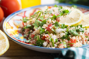Tabbouleh salad with couscous on wooden table. Close up