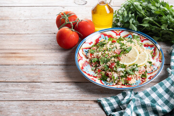 Tabbouleh salad with couscous on wooden table. Copy space