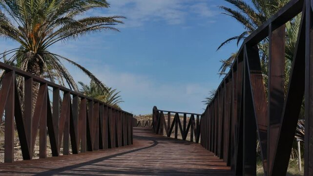Wooden walkway to the beach, light breeze in the palmtrees